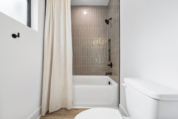 A bathroom with a bathtub, toilet, and a shower area. - Lux A-Frame w/ Hot Tub, Fire Pit, Kayaks & Views (Rockwell)