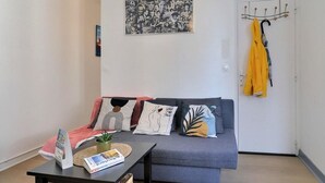 A modern living room with a grey sofa, a coffee table, and a wall-mounted coat rack with a yellow jacket. - Herman's stopover - SAINT MALO (SAINT MALO)