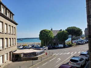 A coastal street with parked cars, a café with outdoor seating, and a view of the sea. - Herman's Stopover - SAINT MALO (SAINT MALO)