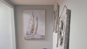 Una stanza con un tavolo in marmo, un quadro di una barca a vela incorniciata, una sedia da ufficio nera e una scatola verde sul tavolo.
