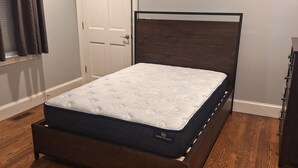 Una camera da letto con un letto in legno, una porta bianca e una ventola a soffitto.