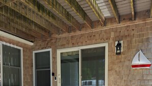 Un patio coperto con un muro in mattoni, ampie porte scorrevoli in vetro e un tavolino con una sedia.