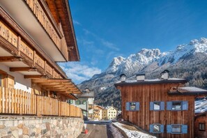 Un edificio de madera con un muro de piedra y una valla de madera, con montañas al fondo.