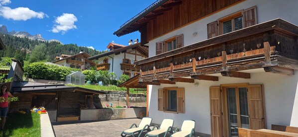 Una chaleta tradicional con balcones de madera, un patio con sillones de descanso y vistas a la montaña.