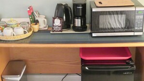 A kitchenette with a coffee maker, microwave, and a trash bin.