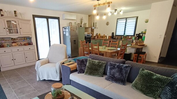 A modern living room with a sofa, dining table, and kitchen in the background. - Gîtes de France® - Chez Fanfan (Unknown)