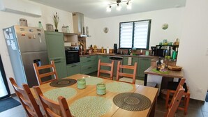 A compact kitchen with a dining area, featuring a refrigerator, microwave, and green cabinets. - Gîtes de France® - Chez Fanfan (Unknown)