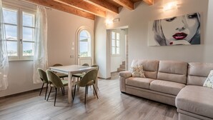 Una sala de estar moderna con comedor, vigas de madera en el techo y un cuadro grande en la pared.
