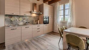 Una cocina moderna con armarios de madera, un horno de acero inoxidable y un comedor con mesa y sillas.