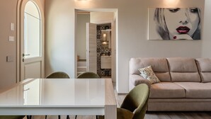 Una sala moderna con un sofá color beige, una mesa de comedor y una cocina al fondo.