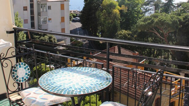 A balcony with a table and two chairs, overlooking a body of water and mountains. - Splendido da aMare (Zoagli)