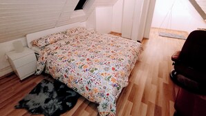 A bedroom with a sloped ceiling, a single bed with floral bedding, a small window, and a wooden floor. - Wellness oasis in a wonderful panoramic location (Weinheim)