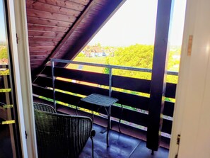 A balcony with a metal railing, a wicker chair, and a small table. - Wellness oasis in a wonderful panoramic location (Weinheim)