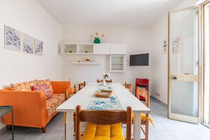 Un coin repas avec une table blanche, un canapé orange et des chaises jaunes.