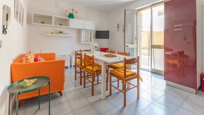 Un espacio habitable compacto con comedor, sofá y televisor instalado en la pared.
