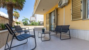 Un patio al aire libre con dos sillones de descanso, una mesita y una planta en maceta.