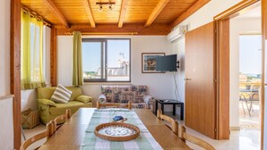 A room with a wooden ceiling, a dining table with chairs, a sofa, a television, and a window with curtains. - Apartment 'Alta Marea' with Sea View, Wi-Fi and Air Conditioning (Ispica)