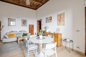 A modern living room with a white sofa, a round dining table, and a wooden cabinet.