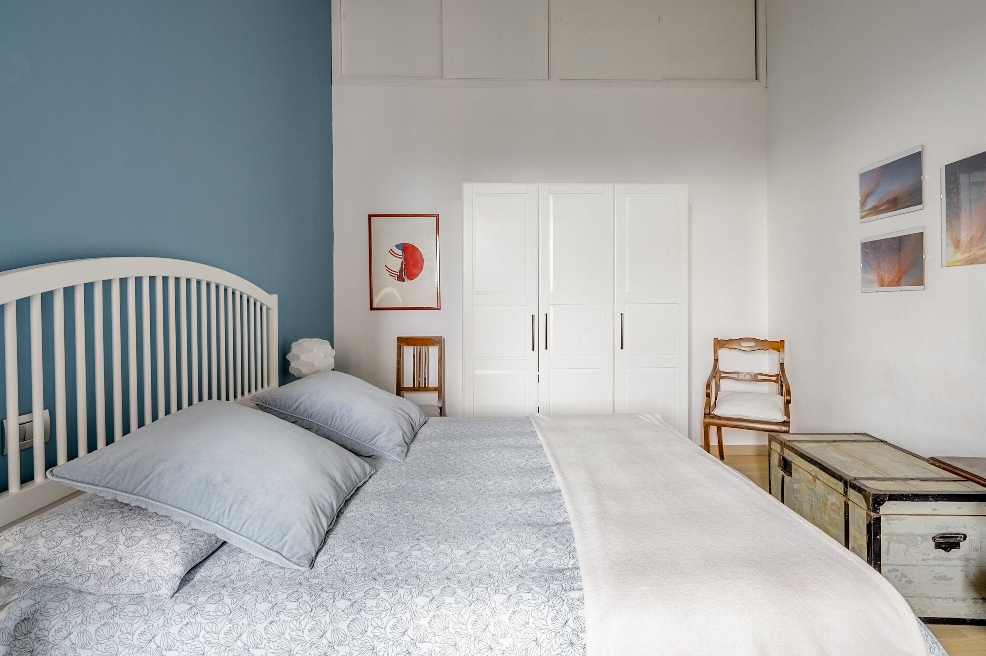 Una camera da letto con una culla, un letto con copriletto decorato, un armadio e una piccola sedia di legno.