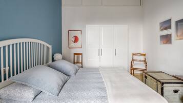 Una camera da letto con una culla, un letto con copriletto decorato, un armadio e una piccola sedia di legno.