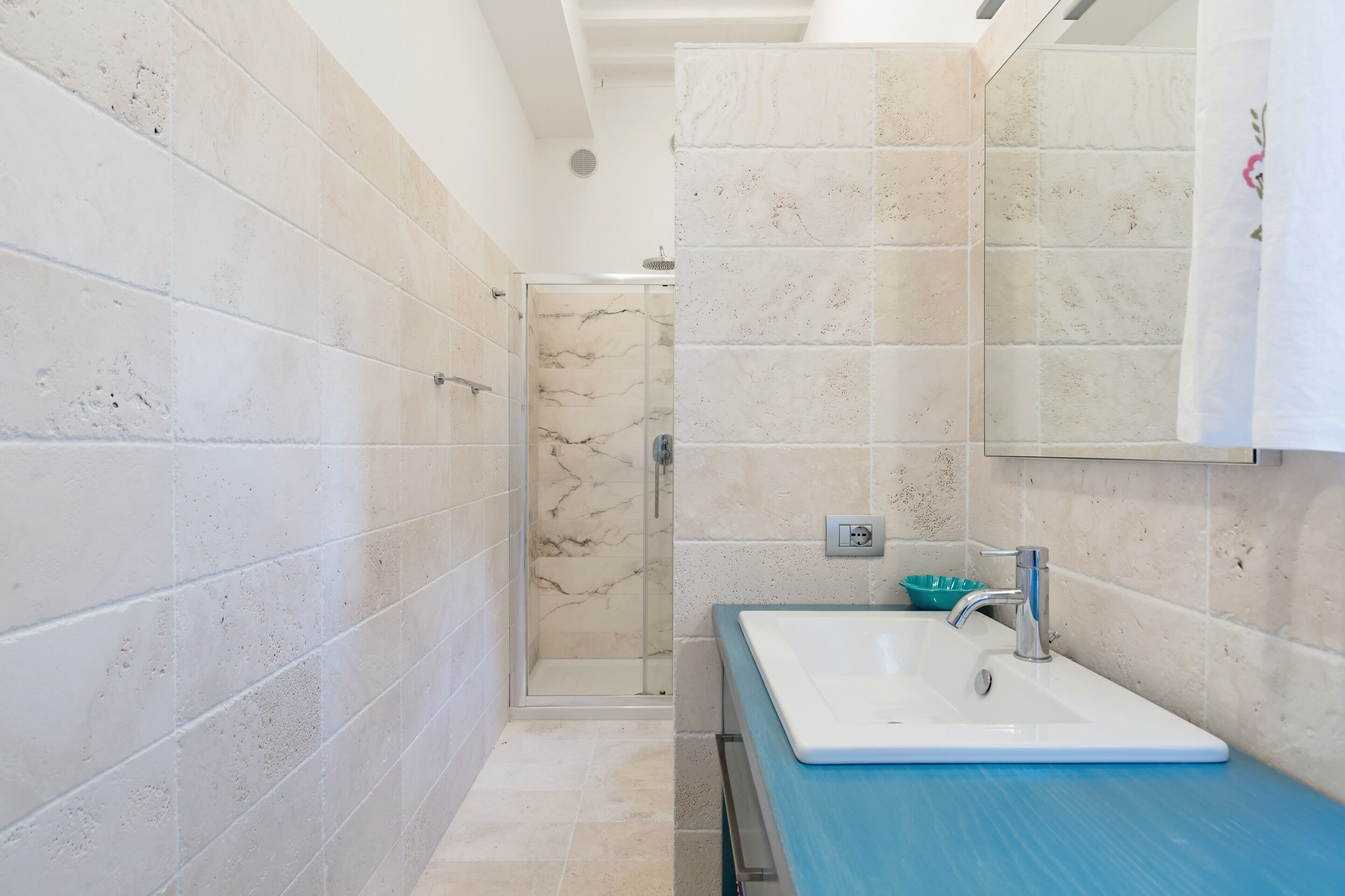Un baño con ducha, lavamanos y espejo.