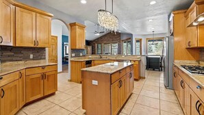 A spacious kitchen with wooden cabinets, a central island, and a chandelier. - 4 BR-7 Bed-Durango Dream House-Incredible Mountain/Golf Views w/ Chef’s Kitchen (Durango)