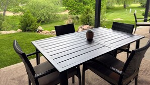 An outdoor patio with a table and chairs, surrounded by greenery and a view of a landscaped garden. - 4 BR-7 Bed-Durango Dream House-Incredible Mountain/Golf Views w/ Chef’s Kitchen (Durango)