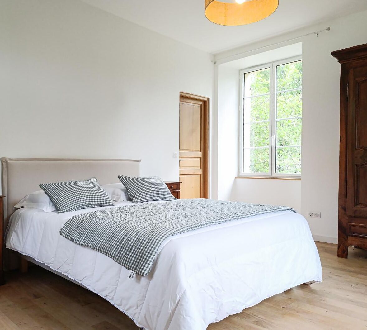 A bedroom with a bed, a window, and a door.