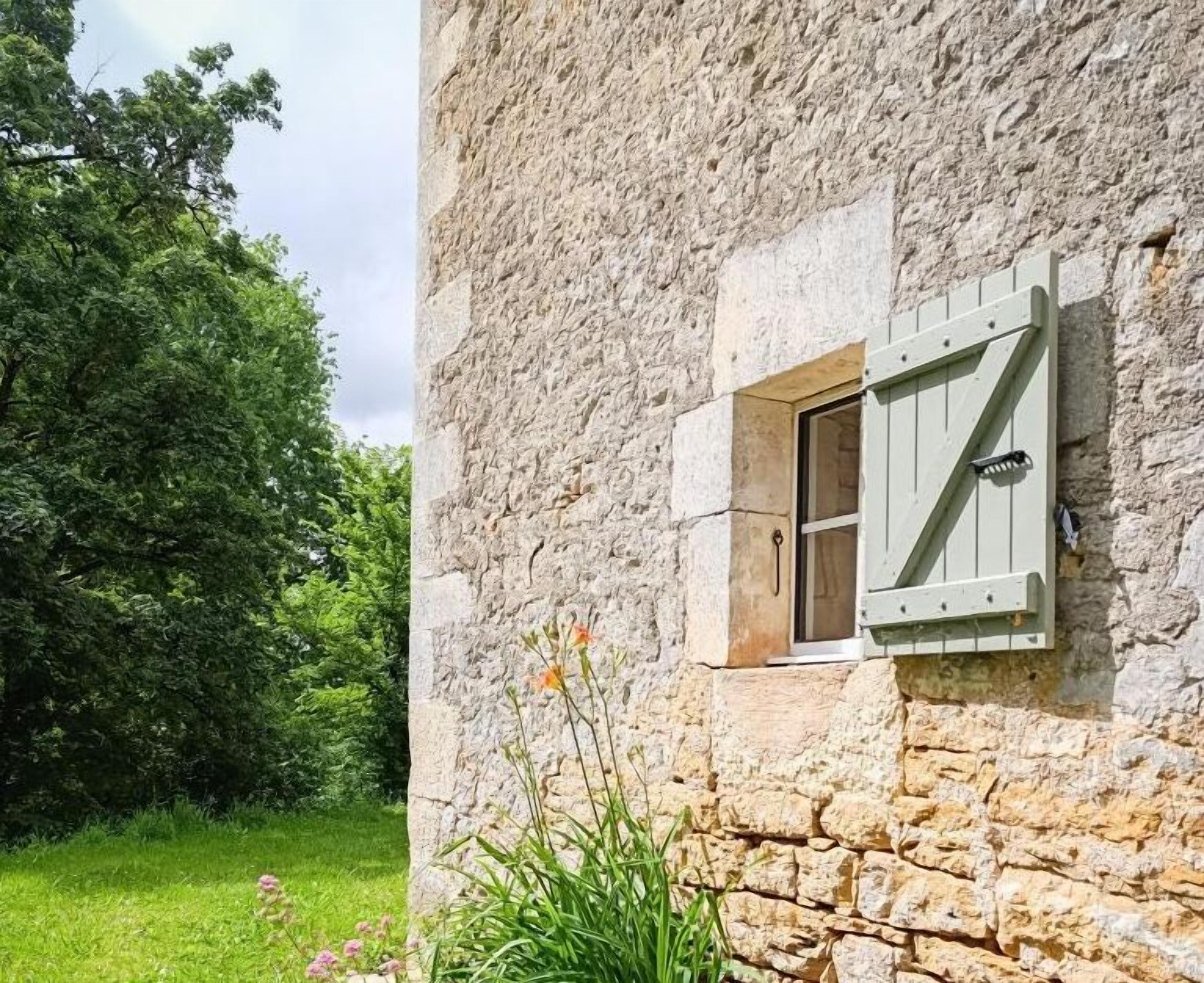 Un edificio de piedra con una ventana que tiene contraventanas de madera.