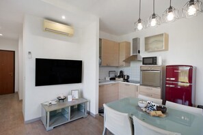 Una cocina moderna con televisión de pantalla plana, microondas, horno y refrigerador rojo.