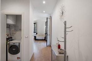 Een wasruimte met een wasmachine, een droogrek en een klein tafeltje met een vaas.