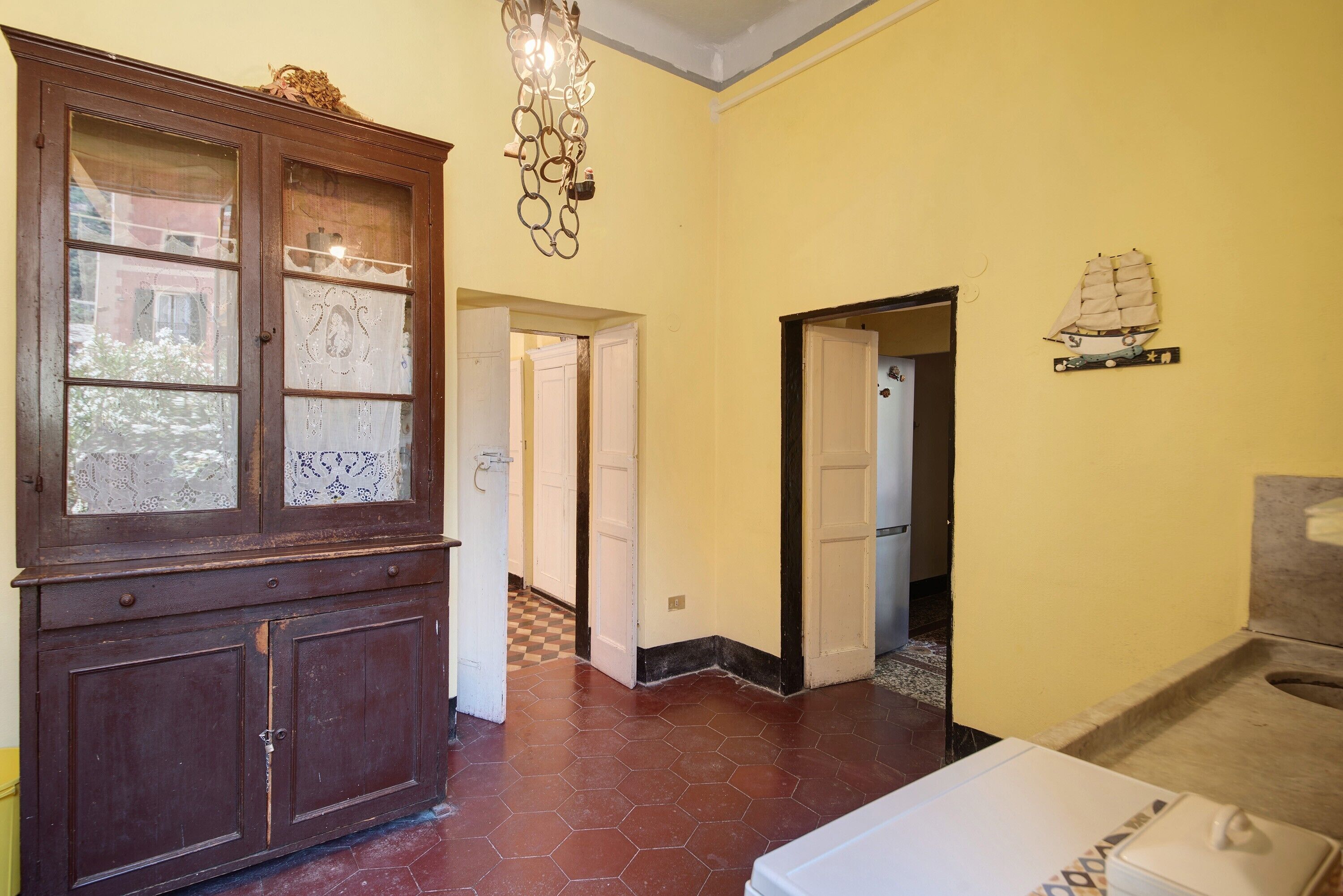 A room with a wooden cabinet, a tiled floor, a white radiator, and a wall-mounted ship decoration.