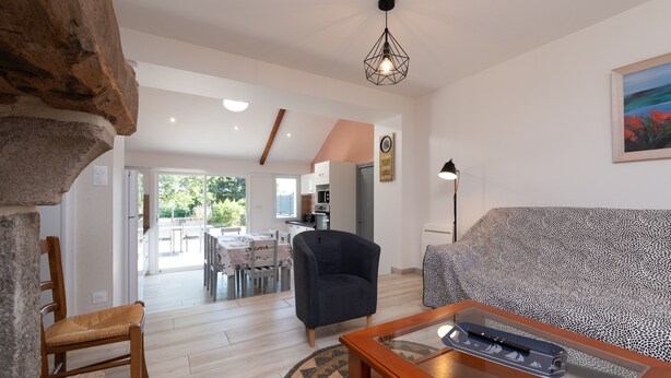 A living room with a sofa, a chair, a coffee table, and a stone accent wall. - Charming House 'Au Pied Des Chênes' with Private Terrace, Shared Garden & Wi-Fi (Crach)