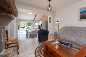 A living room with a sofa, a chair, a coffee table, and a stone accent wall. - Charming House 'Au Pied Des Chênes' with Private Terrace, Shared Garden & Wi-Fi (Crach)