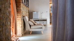Une pièce avec un mur en briques, un canapé blanc avec des coussins, une armoire blanche et une lanterne blanche.
