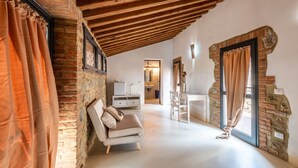 Un loft spacieux avec des murs en briques apparentes, un plafond en bois, un canapé, une table à manger et un coin cuisine.