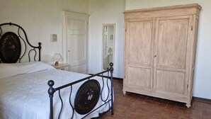 A bedroom with a bed, a nightstand, a lamp, and a wardrobe. - Apartment 'Romantico' – Farm Stay with View of Siena (Monteroni d'Arbia)