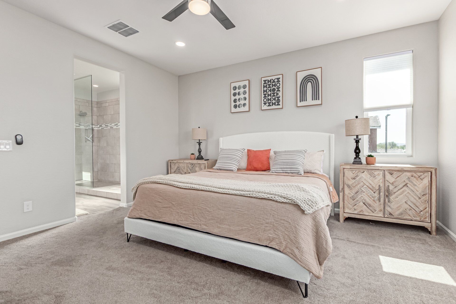 A bedroom with a bed, bedside tables, a window, and artwork on the wall.