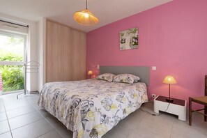 Un dormitorio con cama, lámparas de noche, ventana con vistas y puerta.