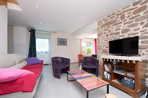 A living room with a sofa, armchairs, a coffee table, a bookshelf, and a television. - Cottage 'La Clé Du Bonheur' with Private Terrace, Shared Garden and Wi-Fi (Crach)