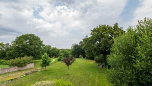 A well-maintained garden with a variety of trees and shrubs, a grassy lawn, and a stone wall. - Cottage 'Le Cocon' with Private Terrace, Shared Garden and Wi-Fi (Crach)