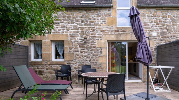 A stone building with a patio area featuring outdoor furniture, including a table and chairs, and a covered umbrella. - Cottage 'Le Cocon' with Private Terrace, Shared Garden and Wi-Fi (Crach)