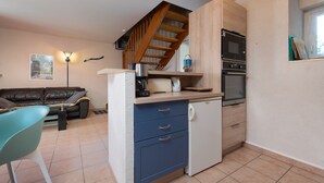 A compact kitchen with a built-in oven, a coffee maker, and a refrigerator.
