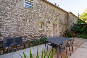 A stone building with a patio area, a table, and chairs. - Cottage 'Mon Nid' with Private Terrace, Shared Garden and Wi-Fi (Crach)