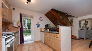 Eine Küche mit Herd, Backofen und einer Holztreppe.
