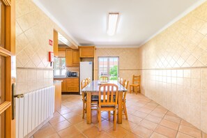Une cuisine équipée d’une table à manger, de chaises, de placards, d’un réfrigérateur et d’une fenêtre.