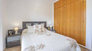 A bedroom with a bed, nightstands, a wooden wardrobe, and a night lamp.