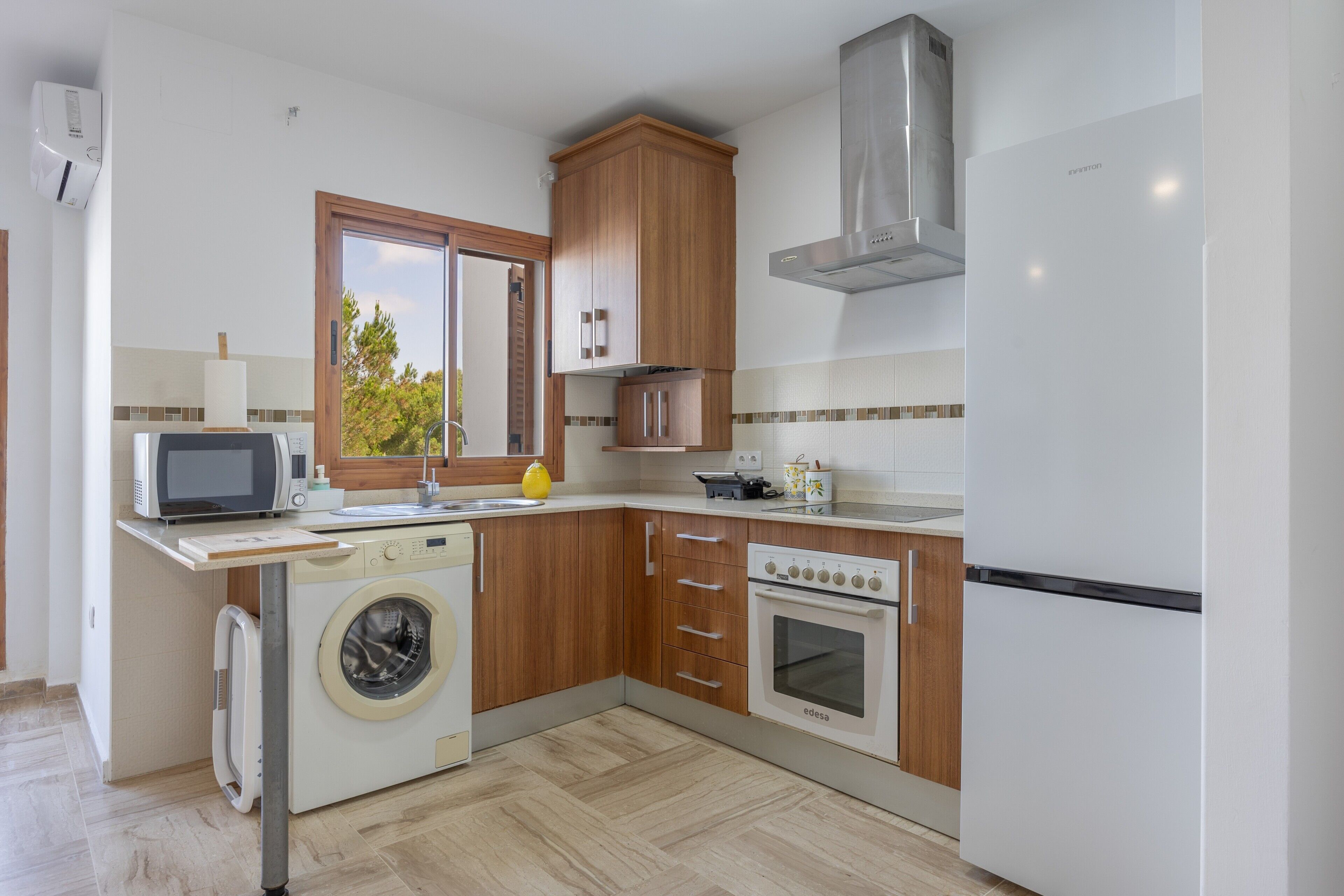 Cocina compacta equipada con lavadora, microondas, horno y refrigerador.