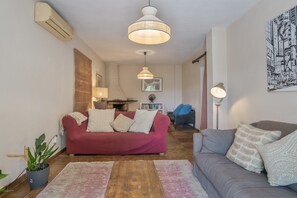 A living room with a red sofa, a grey sofa, a wooden coffee table, a floor lamp, and a wall-mounted air conditioner. - Holiday Home 'Colina' with Mountain View, Private Terrace and Wi-Fi (Vejer de la Frontera)