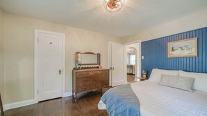 A bedroom with a large bed, a dresser, a mirror, and a painting on the wall. - The Green Acres Cottage - Charming 2 Bedroom near S&T and Acorn Trail in Rolla. (Rolla)